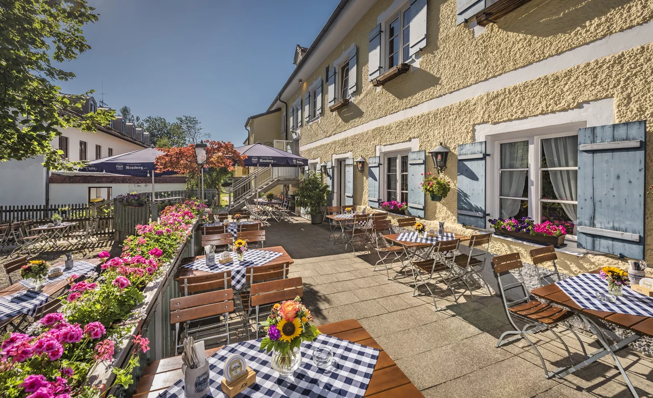 Biergarten in Bichl mit blauen Tischdecken und blühenden Blumenkästen